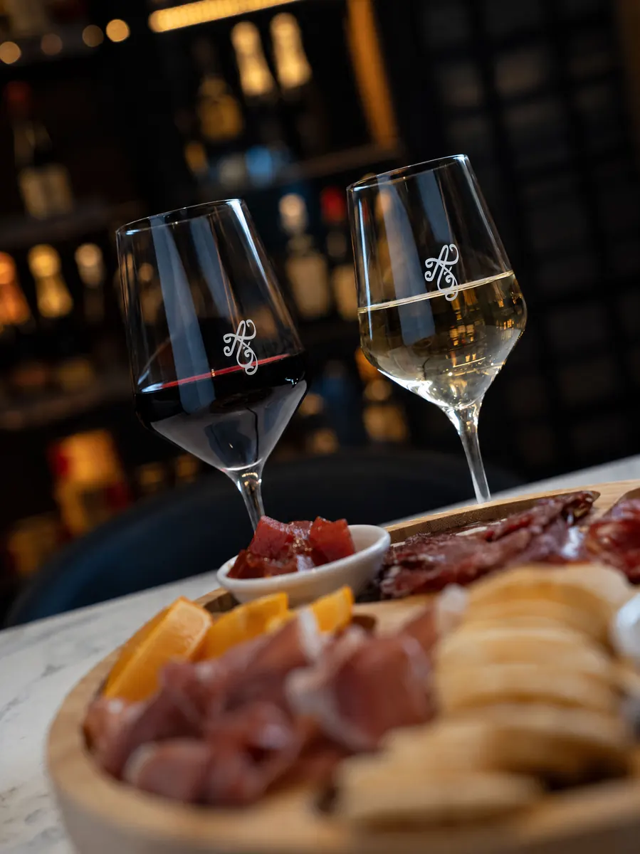 Glasses of red and white wine with charcuterie at Almost French Epicure